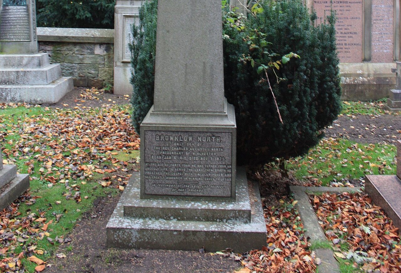Obelisco de granito sobre o túmulo de Brownlow North, com inscrição na base, no Cemitério Dean, em Edimburgo