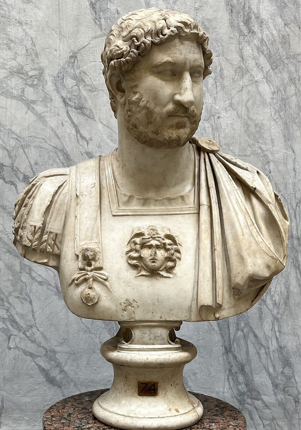 Busto em mármore do imperador Adriano, com os cabelos encaracolados e a barba curta