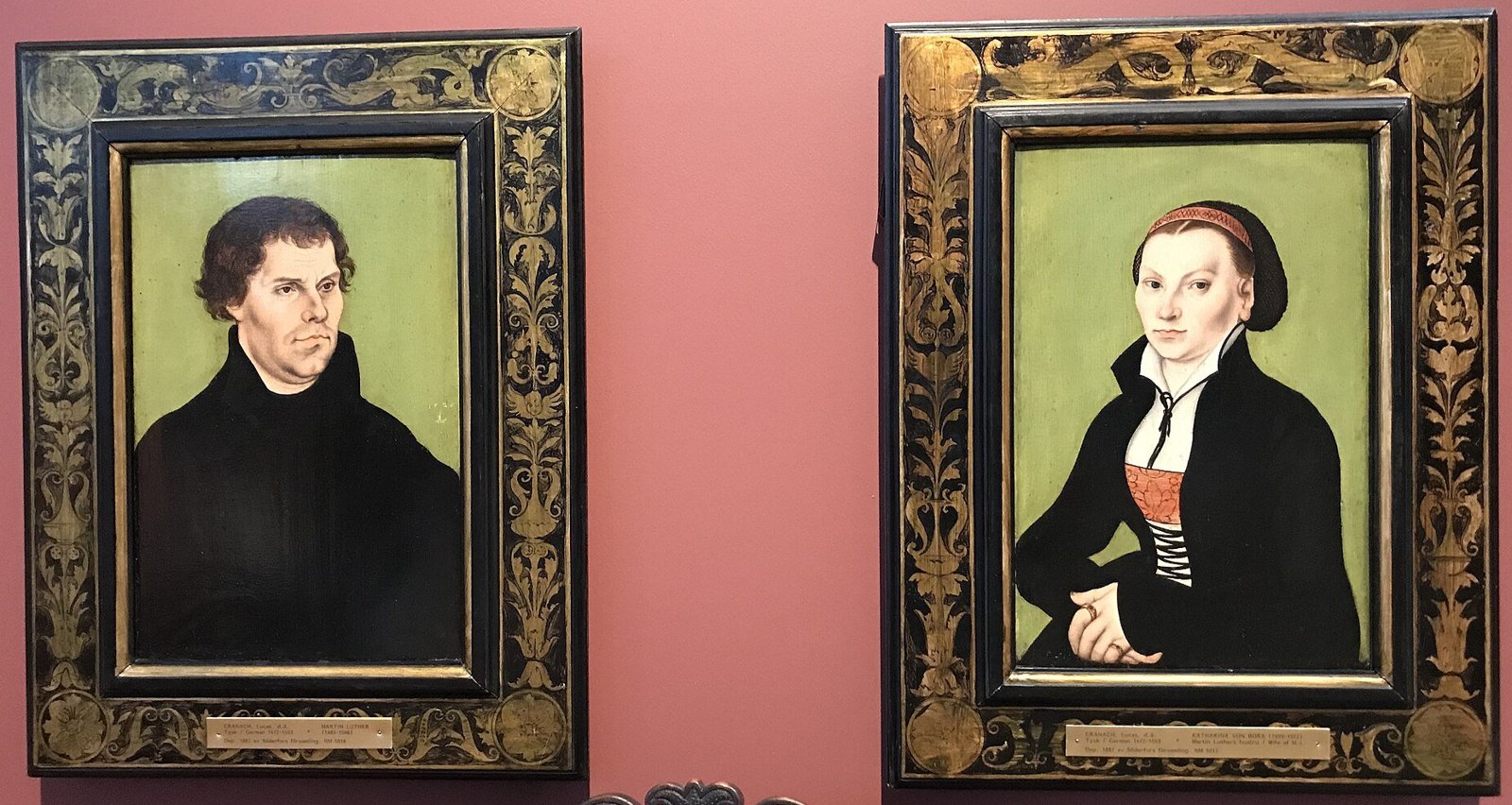 Dois retratos pintados lado a lado: Martinho Lutero, de hábito escuro, e Catarina von Bora, com touca e corpete vermelho, sobre fundo verde
