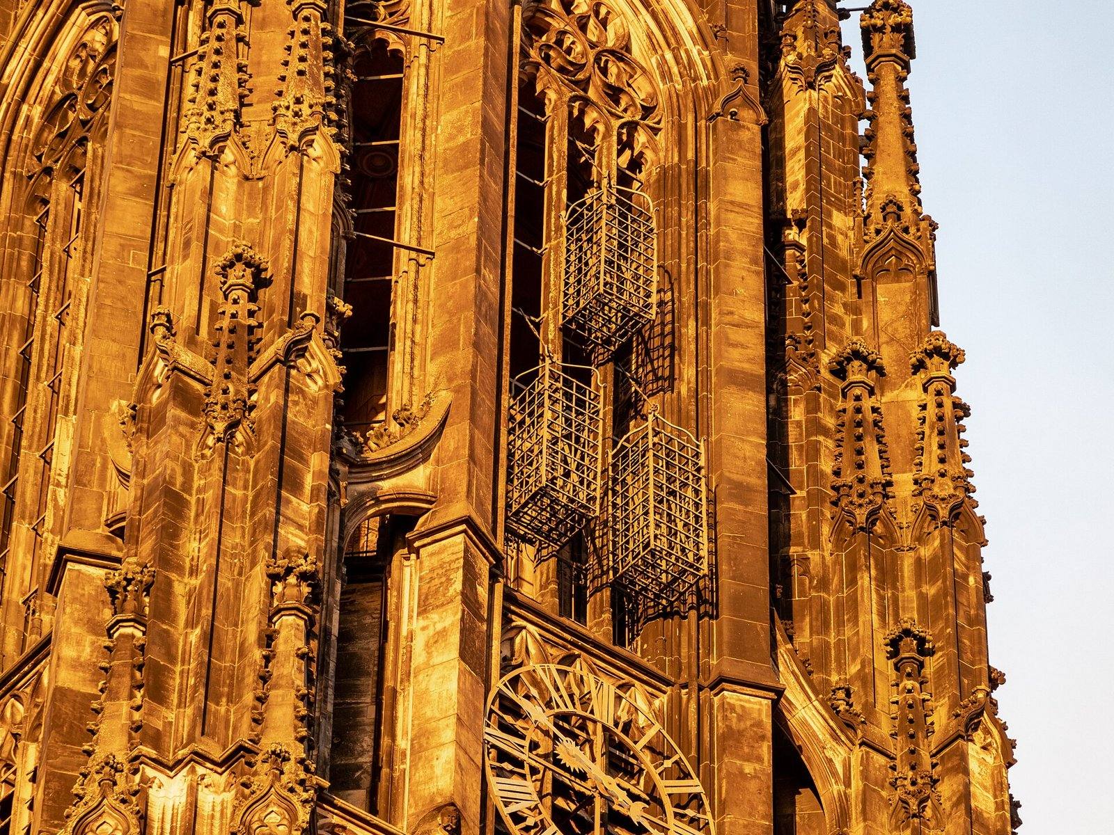 Três gaiolas de ferro penduradas na torre gótica da igreja de São Lamberto, em Münster, iluminadas pelo sol poente