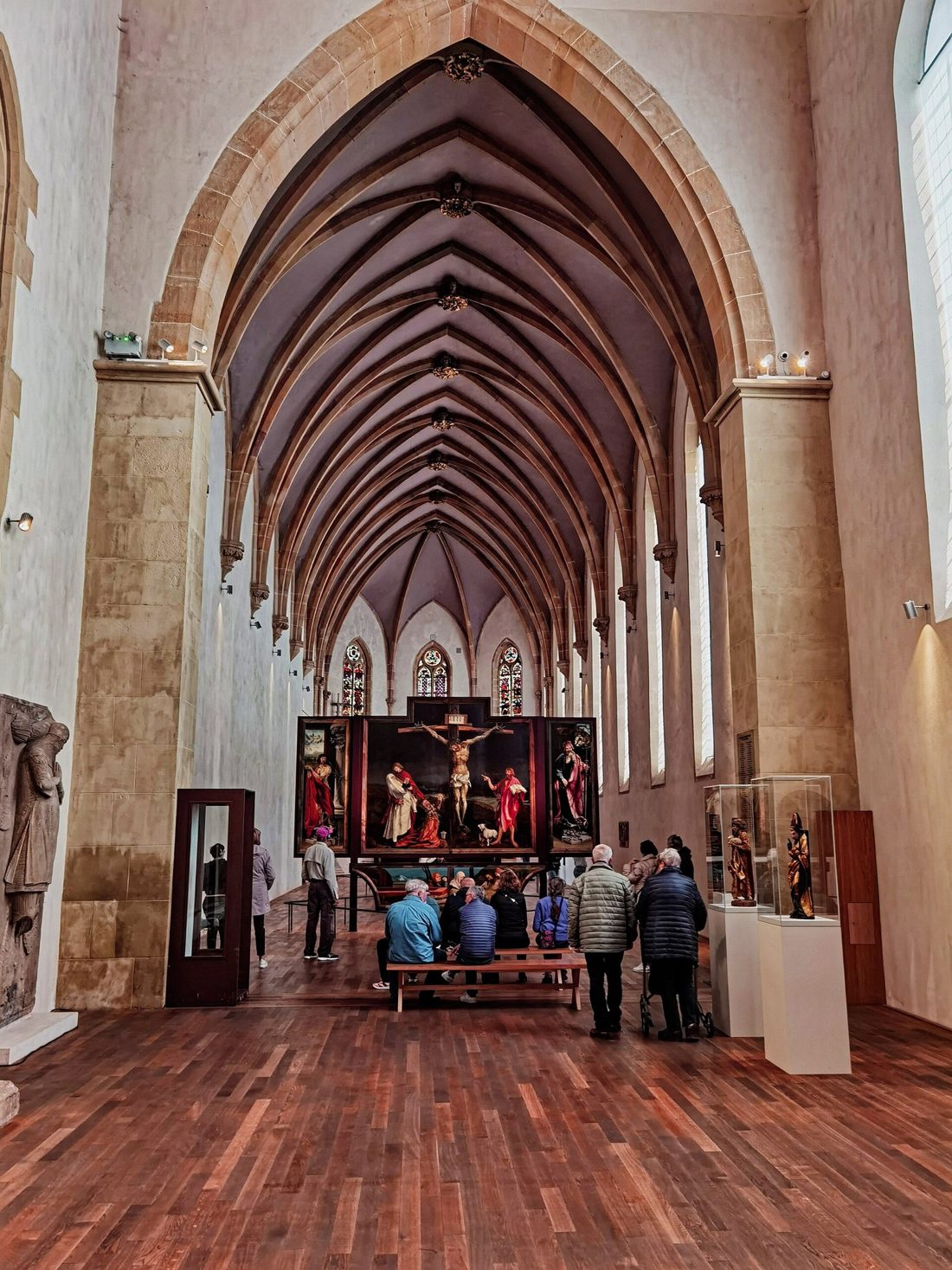 Painel central da Crucificação no Retábulo de Isenheim, com Cristo coberto de feridas na cruz, Maria desfalecida, João e Maria Madalena aos pés, e João Batista apontando para Ele
